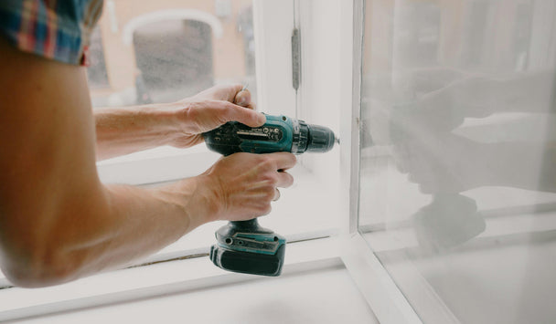 Person using a cordless drill on a window frame