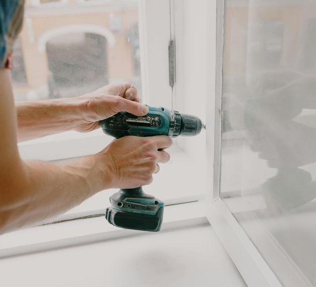 Person using a cordless drill on a window frame