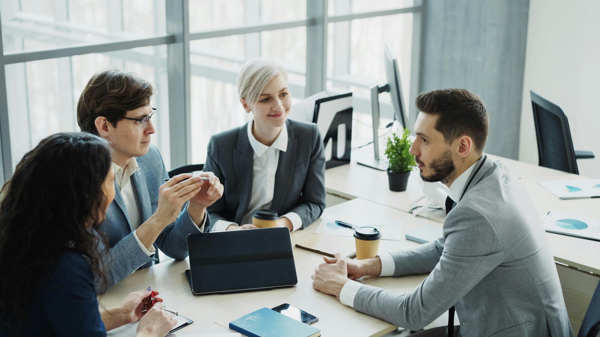 Group of professionals in a meeting around a table in an office setting.