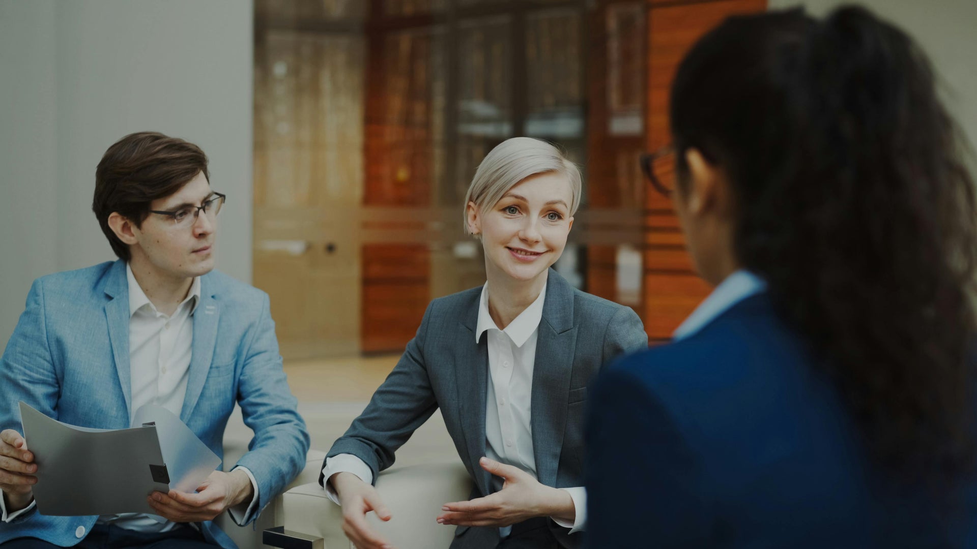 Two professionals in a business setting with a third person partially visible.